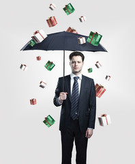 Young Business man with umbrella under gift boxes rain