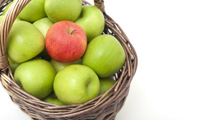 basket with green apples and one red one