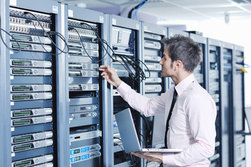 businessman with laptop in network server room