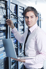 businessman with laptop in network server room