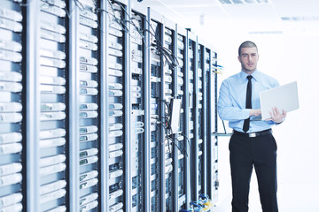 businessman with laptop in network server room