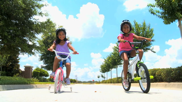 Two Young Ethnic Sisters Riding Their Bicycles
