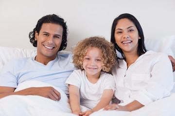 Happy family sitting on the bed together