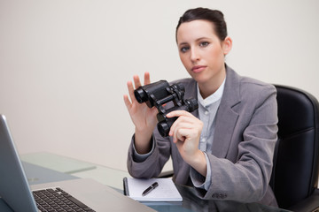 Businesswoman on her desk with binoculars