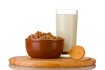 Boiled buckwheat in a brown bowl a glass of milk
