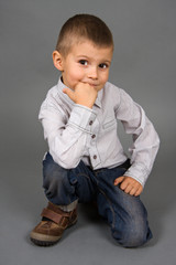 The boy sits on a grey background