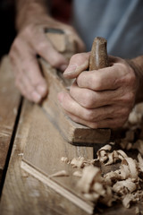 Man hands with carpenter's plane on wooden background