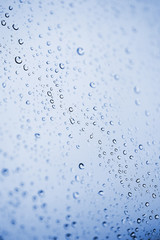 Beautiful abstraction with water drops over blue glass backgroun