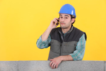 bricklayer on the phone behind concrete wall