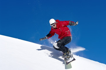 Fototapeta na wymiar Snowboarder jumping through air with deep blue sky