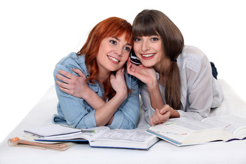 two female students studying listening a mobile