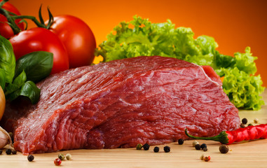Raw beef on cutting board and vegetables