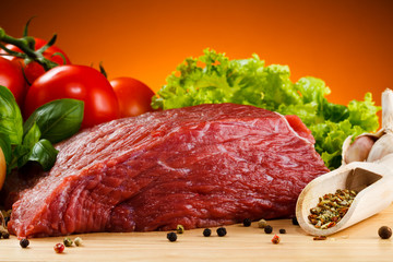 Raw beef on cutting board and vegetables