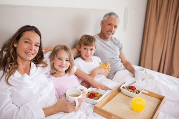 Obraz na płótnie Canvas Happy family having breakfast in a bedroom