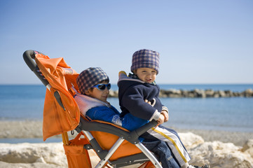 Baby carriage on the beach with brothers.