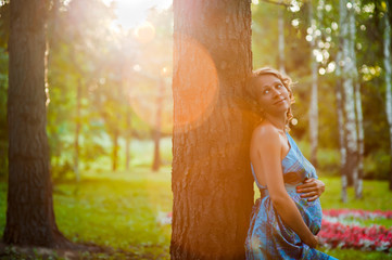 Красивая беременная девушка у дерева в живописном парке © Deksbakh