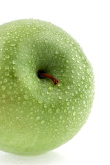 The ripe green apple covered by water drops