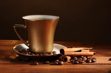 golden cup with coffee, cinnamon and coffee beans