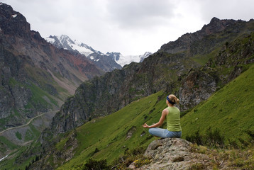 The young girl makes meditation in beautiful mountain gorge