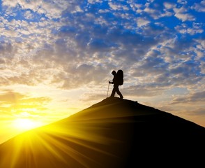 traveler silhouette on a mountain top at the sunset