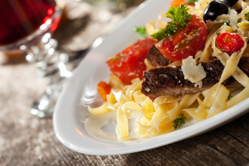 frische Pasta mit Tomaten und Oliven auf einem Teller