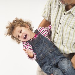father holding and playing with laughing toddler girl