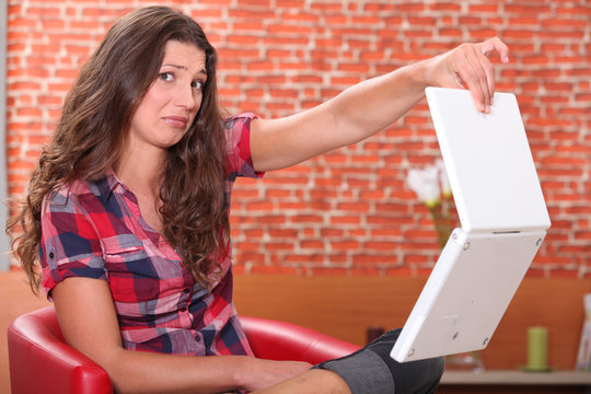 Woman holding her laptop disdainfully