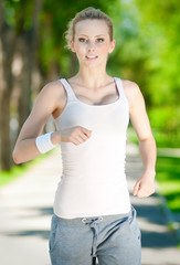 Fototapeta premium Young woman running in green park
