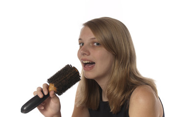 Young teenage girl singing into her hair brush.