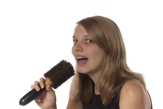 Young Teenage Girl Singing Into Her Hair Brush.