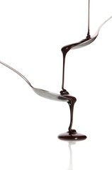 Chocolate poured into a spoon and from it to another spoon