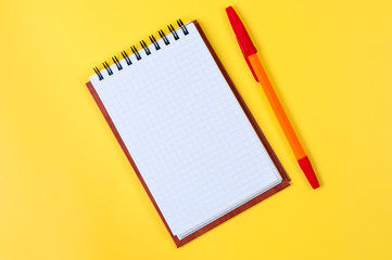 Notepad and pen on yellow background.