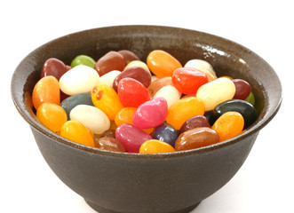 Colourful candies in a bowl on white background
