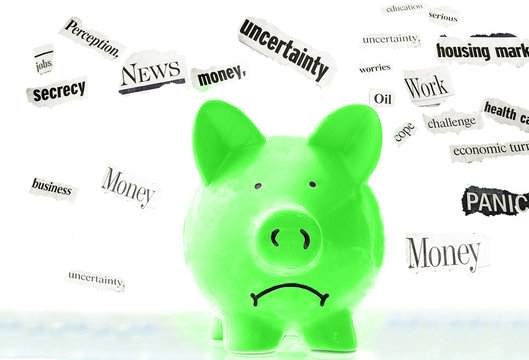 frowning pink piggy bank with bad economic news headlines