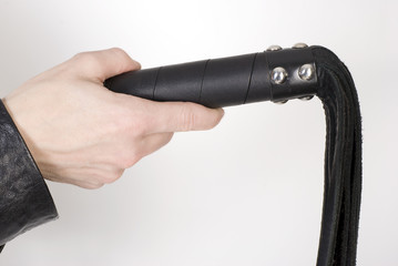 Black Leather Flogging Whip in female hand.