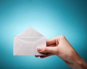 woman's hand holding opened envelope against blue background