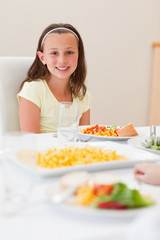 Obraz na płótnie Canvas Smiling girl sitting at dinner table