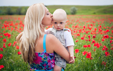 Mother playing with her toddler child in poppy field