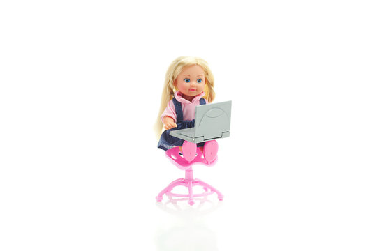 doll sitting on a chair with laptop isolated on white
