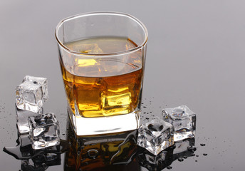 glass of scotch whiskey and ice on grey table