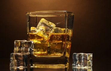 glass of scotch whiskey and ice on brown background