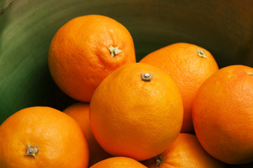 Some oranges fruits in a green bowl