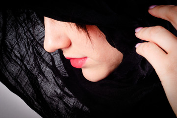 Part of a woman's face with black hood