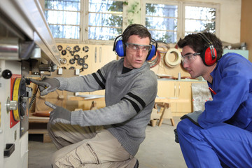 An experienced workman showing an apprentice the ropes