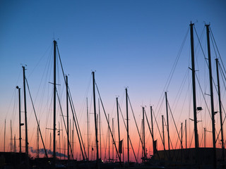 Masts of sail boats in sunset