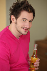 Young man smiling with bottle of beer
