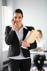 Brunette holding folders and mobile telephone