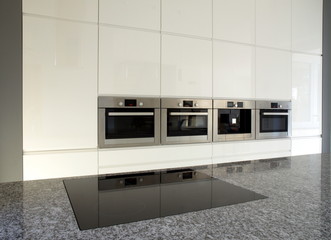 Modern built-in kitchen in white with granite countertop.