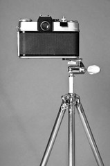 Old film camera and retro steel tripod on grey background