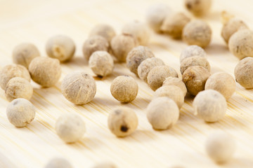 white pepper corns close up on a wooden board